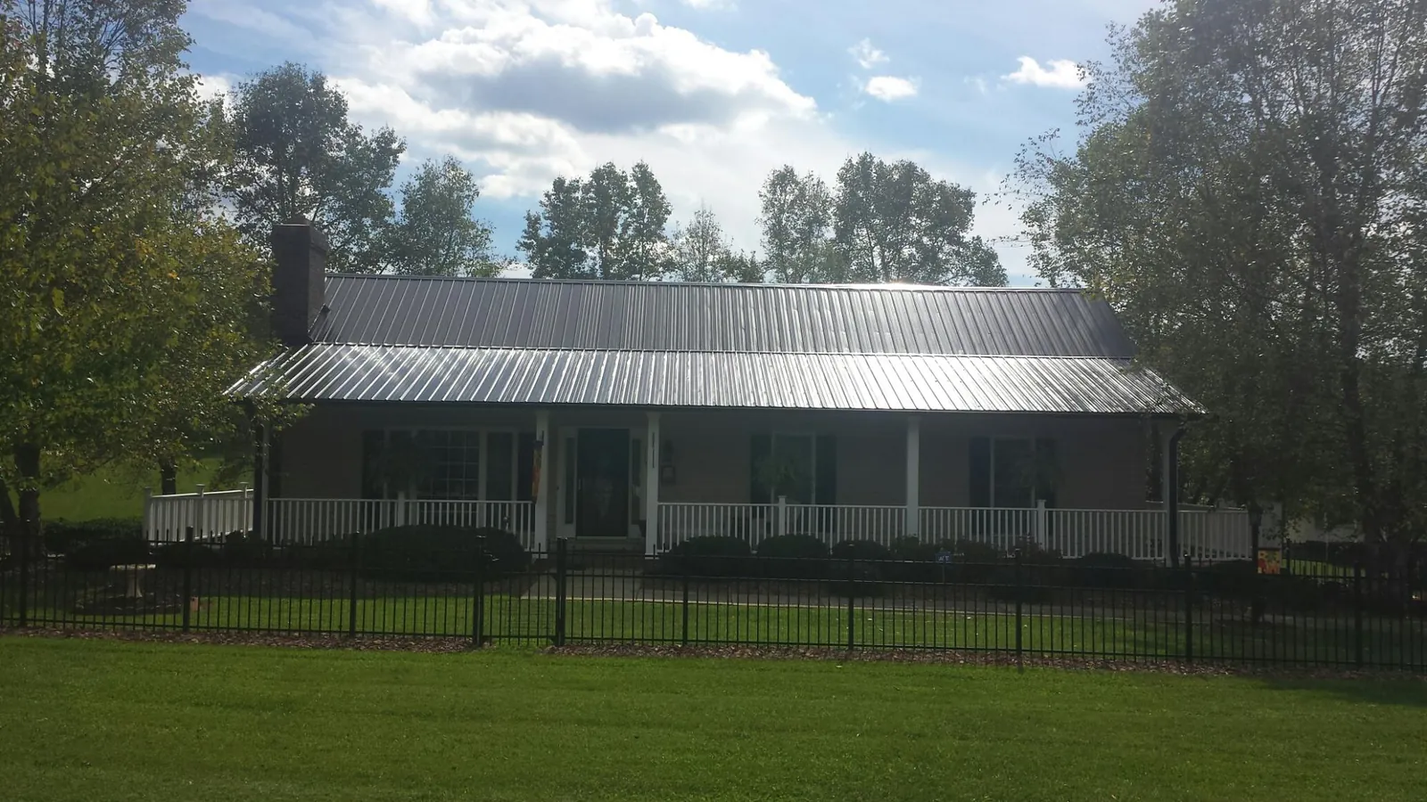Gray metal roof on a brick ranch with a full width front porch — Gutter Guard Installation work by our crew in Ault
