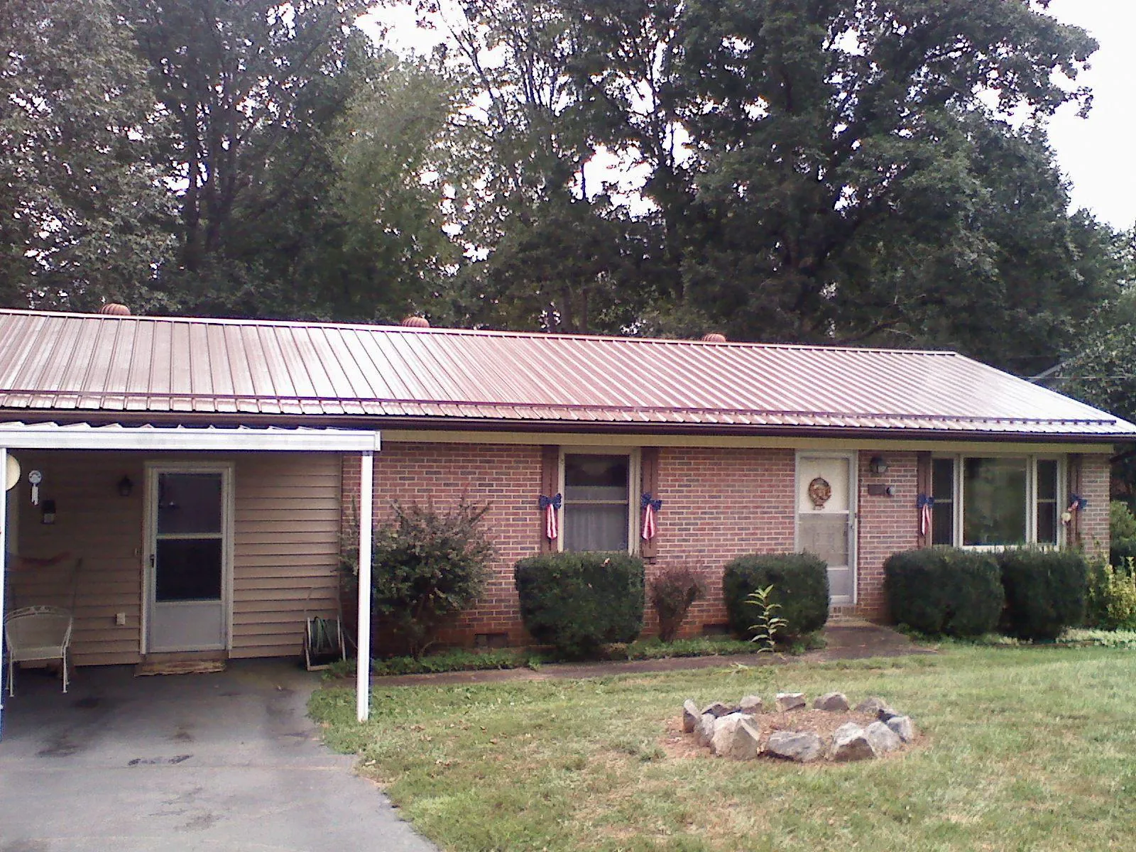 Bronze metal roof and carport on a brick ranch home — Roof Repair work by our crew in Ault