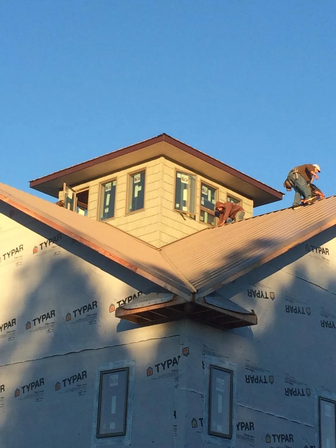 Roofers working around a rooftop cupola on a new metal roof at sunset — Roof Waterproofing in Ault by Roofing Brothers